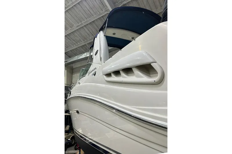 Slide: The Image of 2007 Sea Ray Sundancer 260 boat in indoor storage, showcasing sleek white exterior. - 2