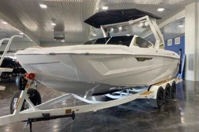 The Image of 2026 Tigé Ultré 25ZX boat on trailer in showroom, sleek design, white exterior. - 0