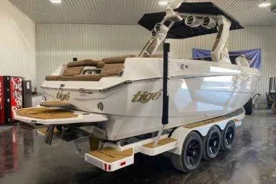 Slide: The Image of 2026 Tigé Ultré 25ZX boat in showroom, featuring sleek design and triple-axle trailer. - 5