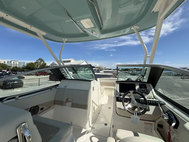 Slide: The Image of The image shows the cockpit of a 2026 Boston Whaler 240 Vantage. It features a modern design with a sleek helm and large steering wheel. Buildings and a clear sky are visible in the background. - 13