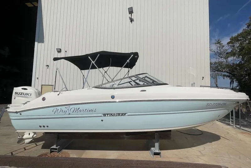 The Image of 2020 Stingray 231 DC boat with canopy, parked outside a building. - 0