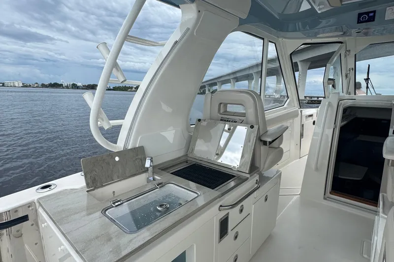 Slide: The Image of 2018 Boston Whaler 380 Realm interior with sink and seating, overlooking calm waters. - 10