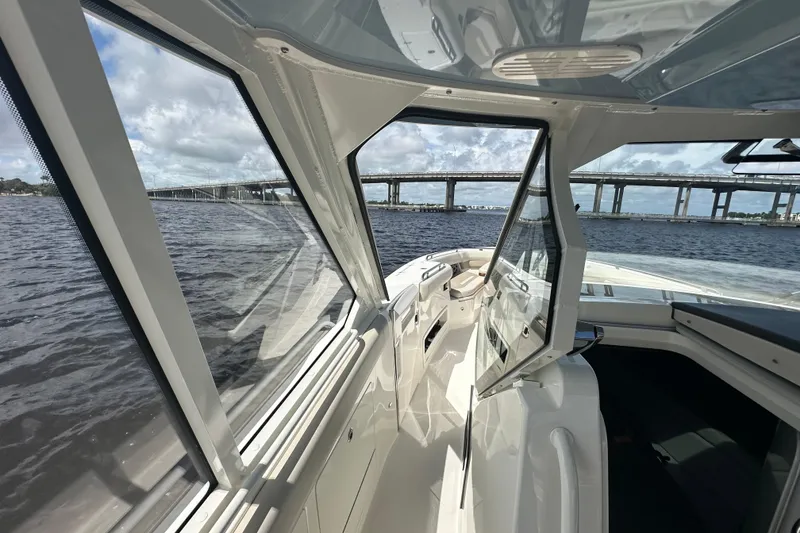 Slide: The Image of 2023 Boston Whaler 380 Realm interior view with open windows, overlooking a bridge and water. - 17