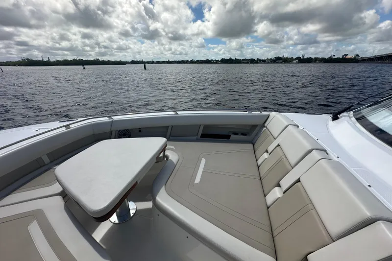 Slide: The Image of 2023 Boston Whaler 380 Realm boat interior with seating and table, overlooking calm waters. - 18