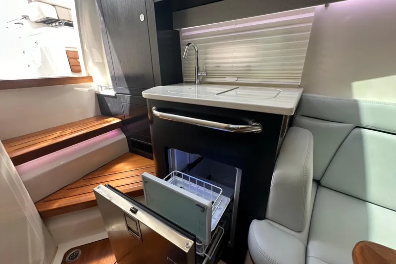 Slide: The Image of 2023 Boston Whaler 380 Realm interior with kitchenette, sink, and seating area. - 23