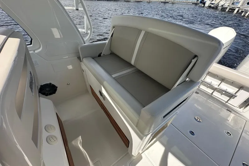 Slide: The Image of 2023 Boston Whaler 380 Realm boat interior with cushioned seating and water view. - 9