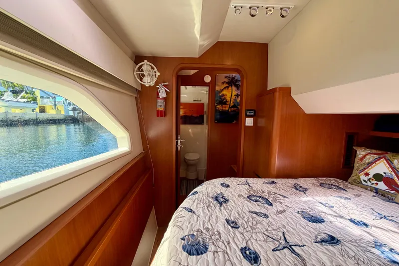 Slide: The Image of Interior of 2017 Aquila 44 Yacht cabin with bed, window view, and wooden decor. - 34