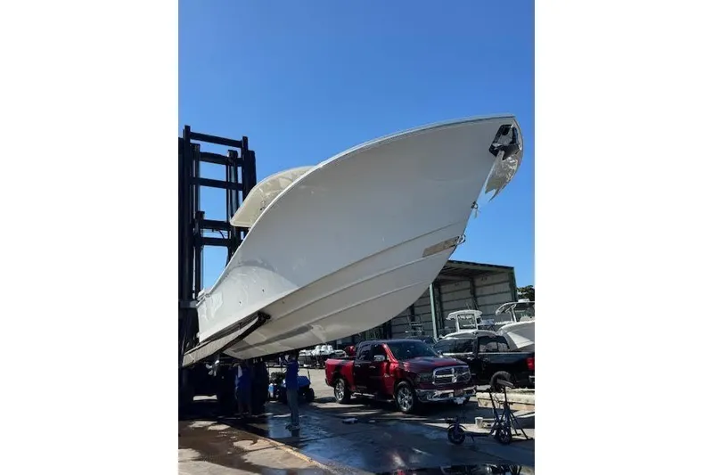 Slide: The Image of 2018 Regulator 34 Center Console boat lifted by forklift in a marina setting. - 1