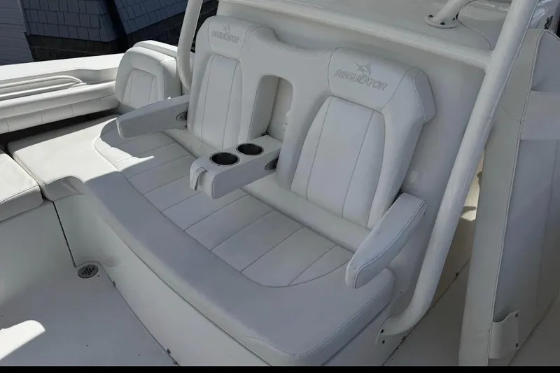 Slide: The Image of 2018 Regulator 34 Center Console boat with white cushioned seating and cup holders. - 13