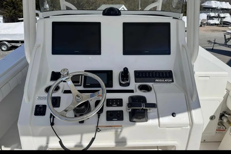 Slide: The Image of 2018 Regulator 34 Center Console helm with dual screens and steering wheel. - 17
