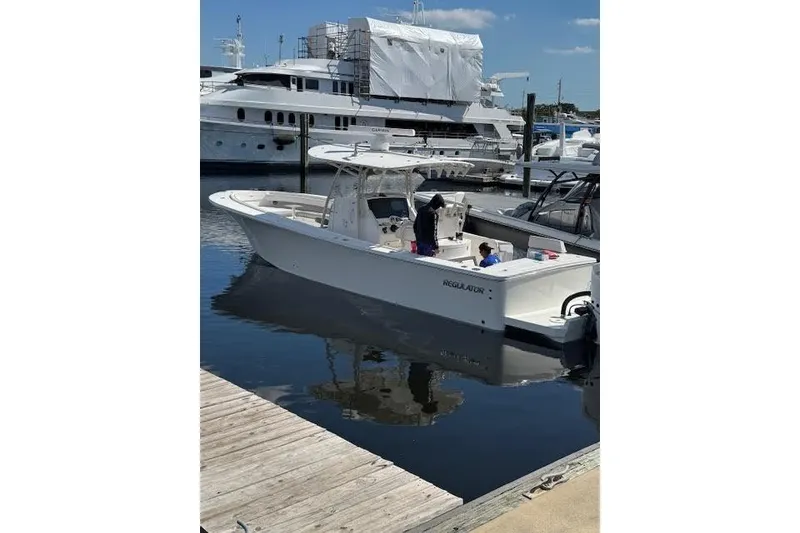 Slide: The Image of 2018 Regulator 34 Center Console boat docked at marina with yachts in background. - 5