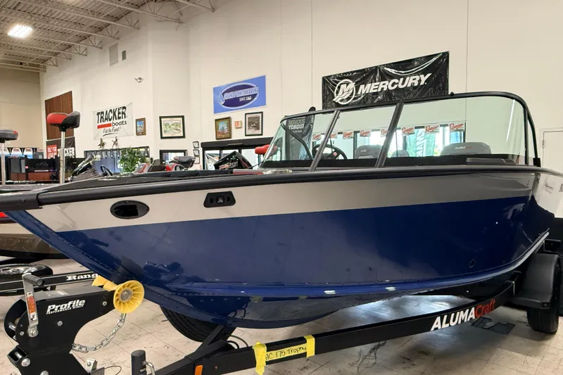 The Image of 2025 Alumacraft Trophy 175X Sport boat displayed indoors on a trailer. - 0