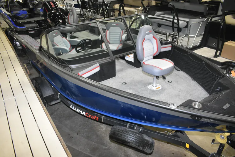Slide: The Image of 2026 Alumacraft Trophy 175X Sport boat with gray and red seating, displayed indoors. - 13