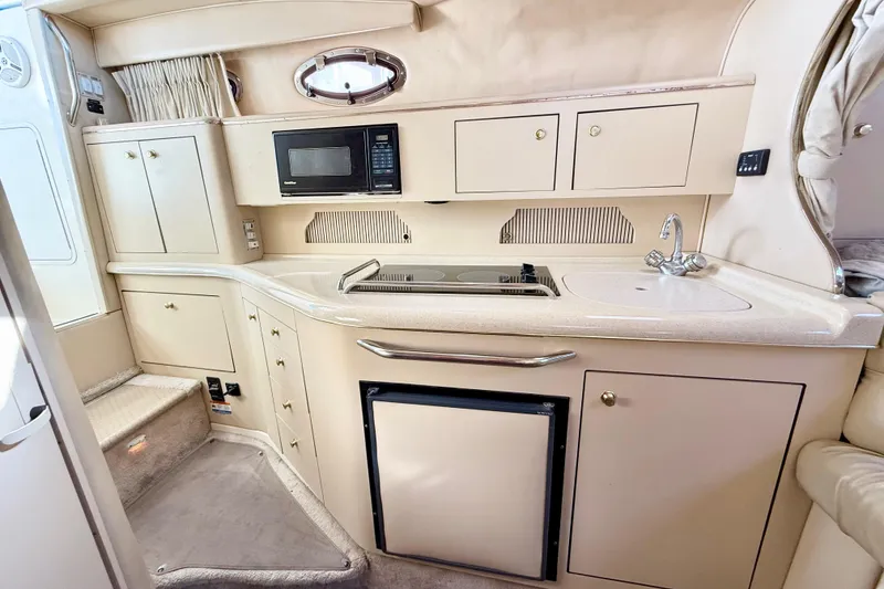 Slide: The Image of 1998 Sea Ray Sundancer 310 yacht kitchen with microwave, stove, sink, and storage cabinets. - 17
