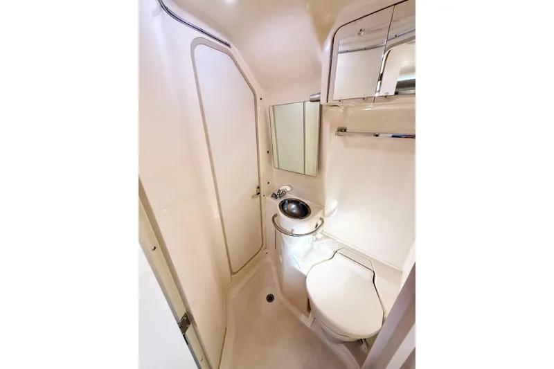 Slide: The Image of 1998 Sea Ray Sundancer 310 bathroom with compact design, featuring sink, toilet, and mirror. - 21