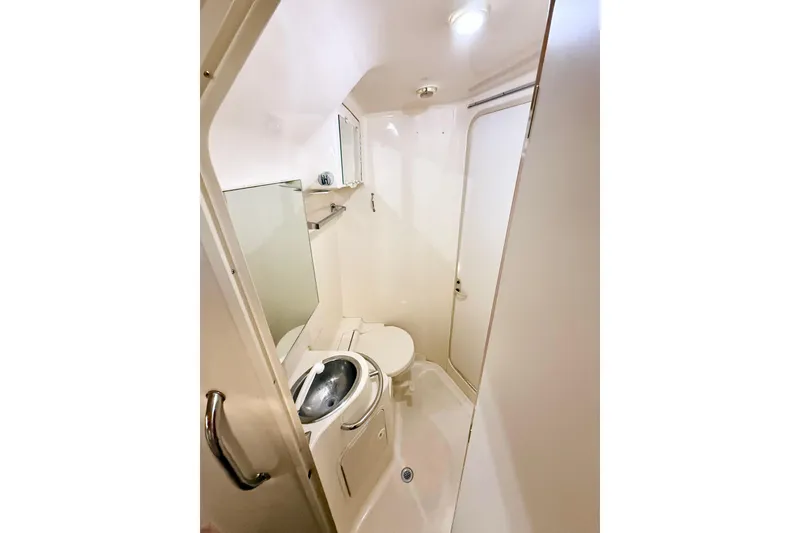 Slide: The Image of 1998 Sea Ray Sundancer 310 bathroom with compact design, featuring a toilet and sink. - 22
