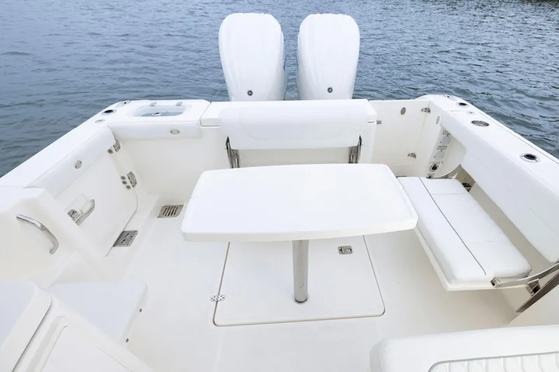 Slide: The Image of 2026 Pursuit DC 286 Dual Console boat interior with seating and table on water. - 15