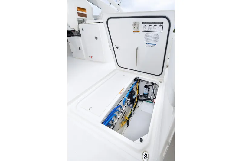 Slide: The Image of 2026 Pursuit DC 286 Dual Console boat storage compartment with open hatch, showcasing internal components. - 17