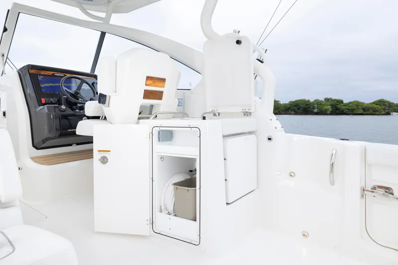 Slide: The Image of 2026 Pursuit DC 286 Dual Console interior with helm and storage, overlooking serene water. - 22