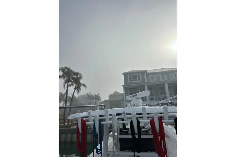 Slide: The Image of 2024 Fountain 38 Center Console boat docked near waterfront homes in foggy weather. - 2