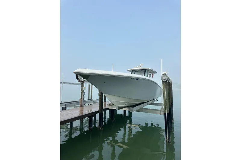Slide: The Image of 2024 Fountain 38 Center Console boat on lift, docked over calm water. - 22