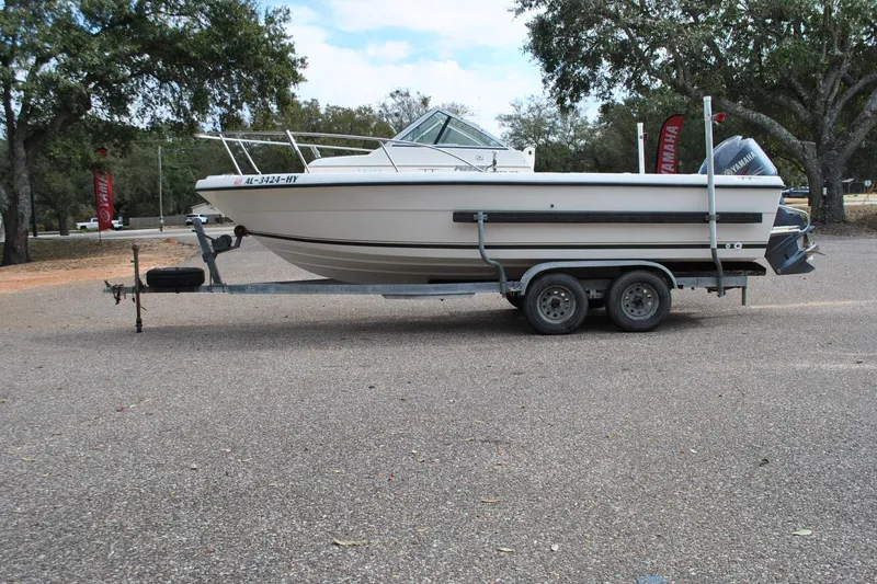 The Image of 1996 Pursuit 2150 Walkaround boat on trailer, parked outdoors. - 1