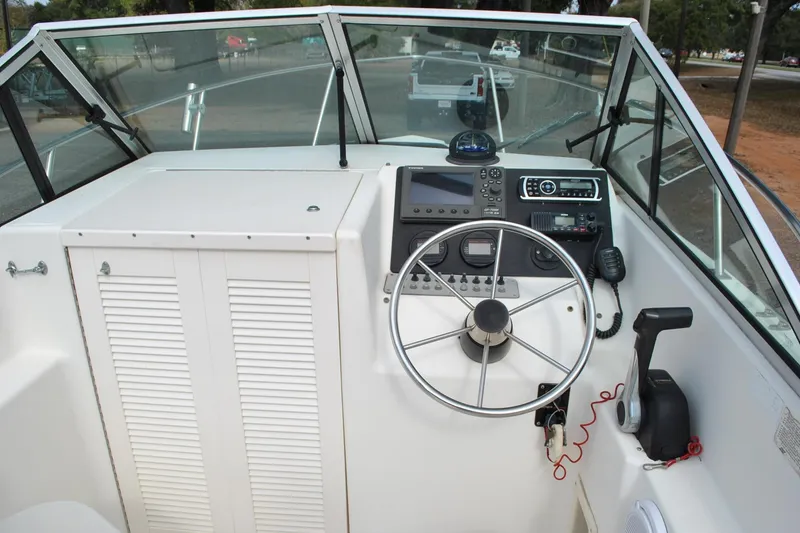 Slide: The Image of 1996 Pursuit 2150 Walkaround boat cockpit with steering wheel and control panel. - 13