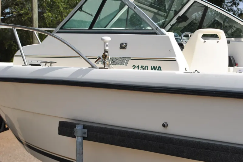 Slide: The Image of 1996 Pursuit 2150 Walkaround boat, white exterior, docked with visible railing and cabin. - 23