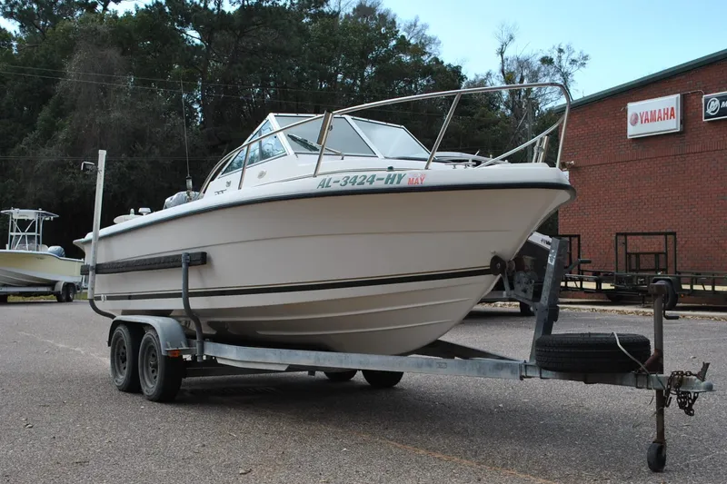 Slide: The Image of 1996 Pursuit 2150 Walkaround boat on trailer, parked outdoors near Yamaha signage. - 4