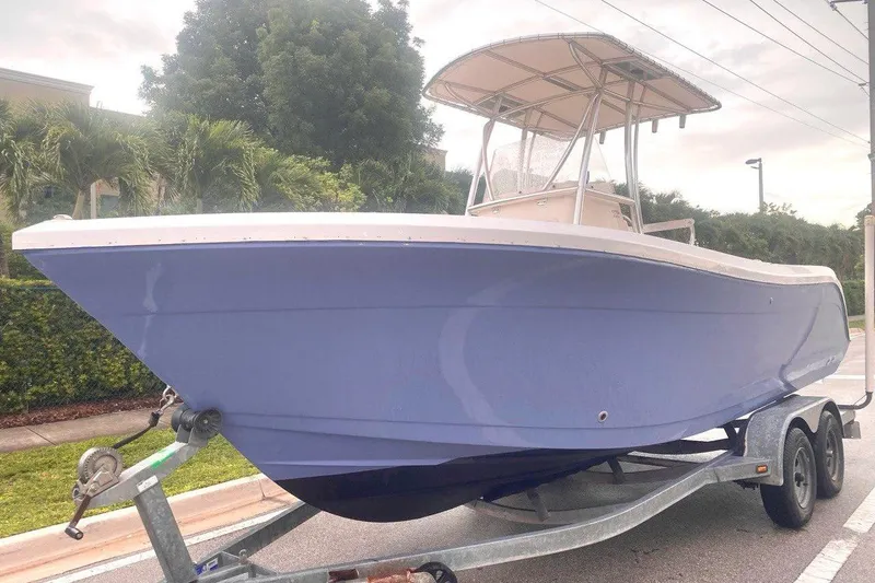 Slide: The Image of 2019 Cobia 220 Center Console boat on trailer, parked outdoors. - 2