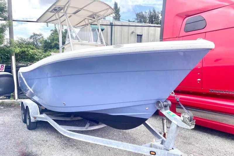Slide: The Image of 2019 Cobia 220 Center Console boat on trailer, parked beside a red truck. - 3