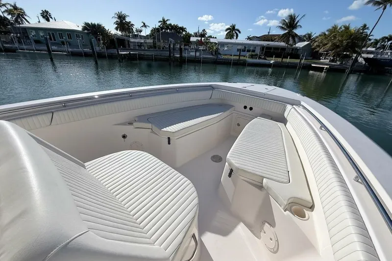 Slide: The Image of 2011 Grady-White Canyon 336 boat interior with white seating, docked by waterfront homes. - 23