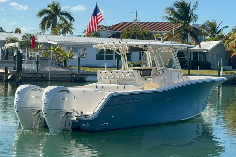Slide: The Image of 2011 Grady-White Canyon 336 boat docked, featuring twin Yamaha engines, palm trees in background. - 4