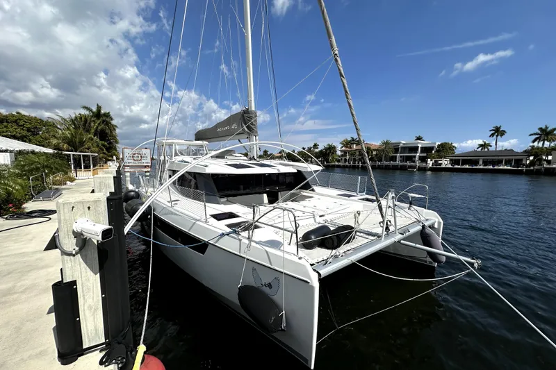 The Image of 2022 Leopard 45 catamaran docked by a scenic waterfront with palm trees. - 1