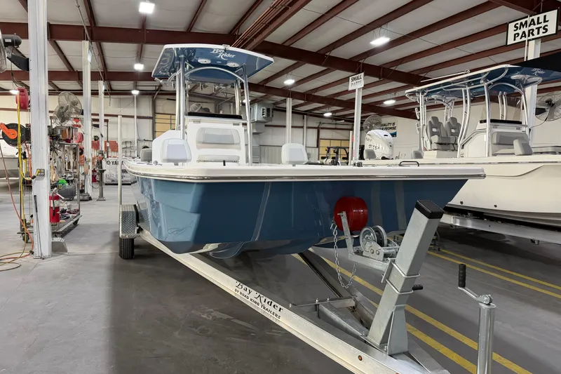 Slide: The Image of 2026 Bay Rider 2460 FS Skiff displayed at a boat dealership under clear blue skies. - 2
