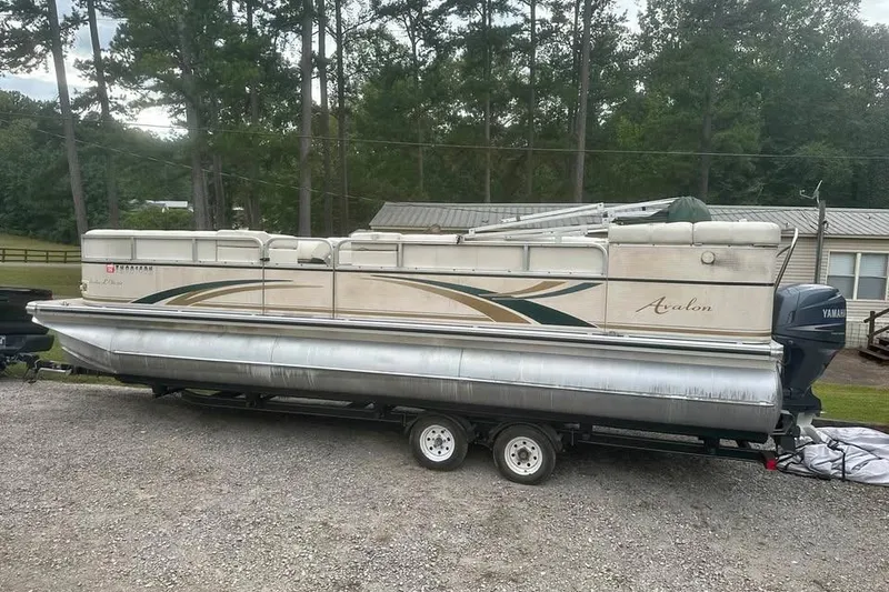 The Image of 2006 Avalon Paradise 24' pontoon boat on trailer, parked outdoors. - 1