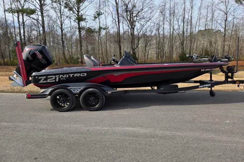 The Image of 2022 Nitro Z21 XL boat on trailer, parked on road with forest background. - 0