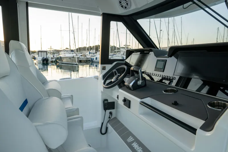Slide: The Image of Interior of 2026 Wellcraft 28 Explorer boat with modern dashboard and marina view. - 14