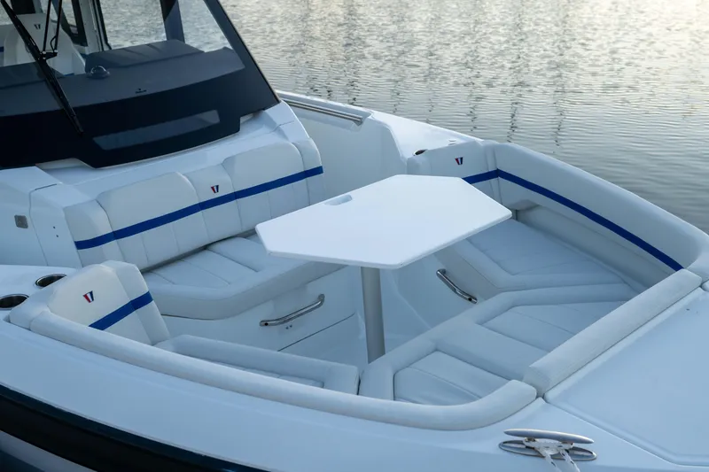 Slide: The Image of 2026 Wellcraft 28 Explorer boat interior with white seating and table, docked on calm water. - 23