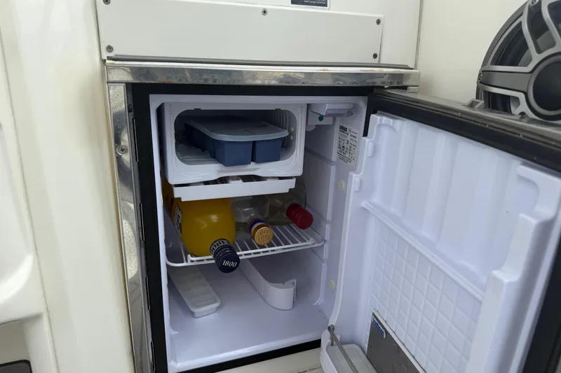 Slide: The Image of Open mini fridge on 2010 Triton 351 Express boat, stocked with beverages and ice tray. - 21