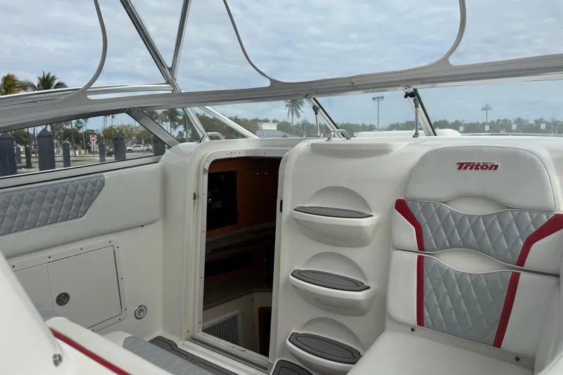 Slide: The Image of 2010 Triton 351 Express boat interior with cushioned seating and cabin entrance. - 22