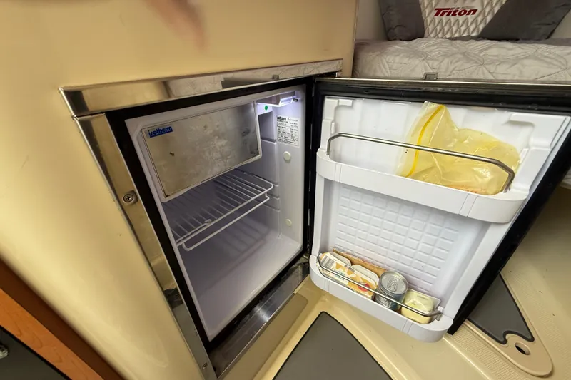 Slide: The Image of Open mini fridge inside 2010 Triton 351 Express boat cabin, showing contents and interior. - 35