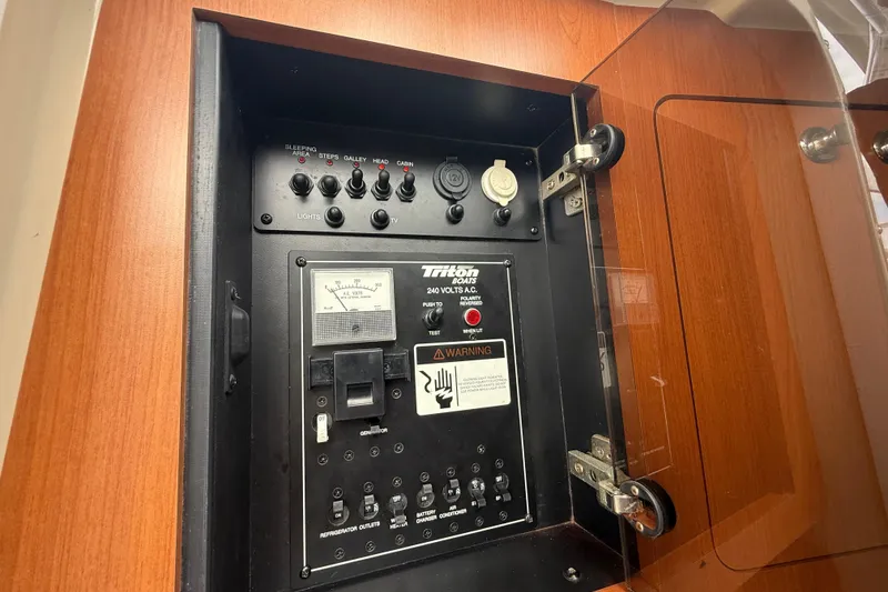 Slide: The Image of Electrical panel of 2010 Triton 351 Express boat with switches and warning labels. - 38