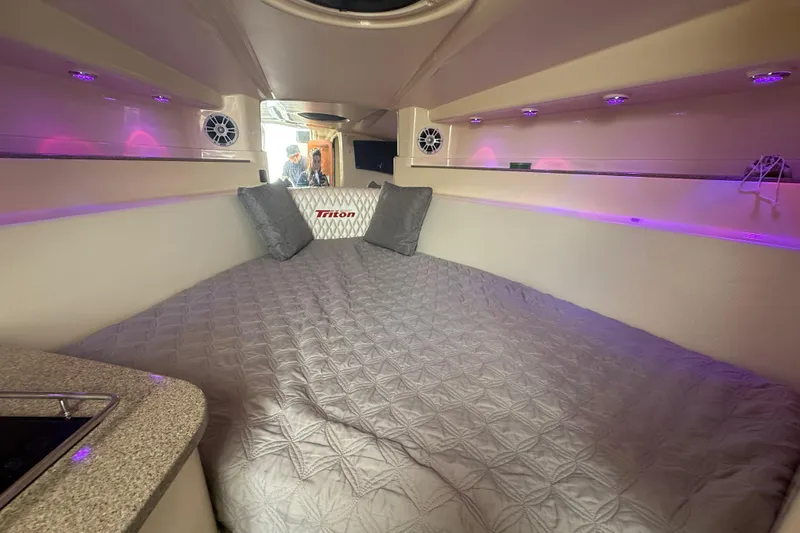 Slide: The Image of Interior cabin of 2010 Triton 351 Express boat with cozy bedding and ambient lighting. - 40