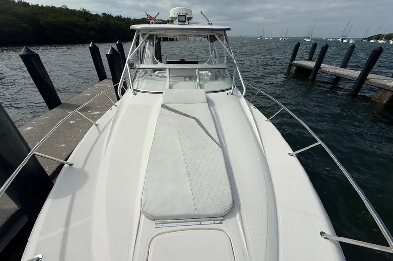 Slide: The Image of 2010 Triton 351 Express boat docked by the water, featuring a sleek white deck. - 46