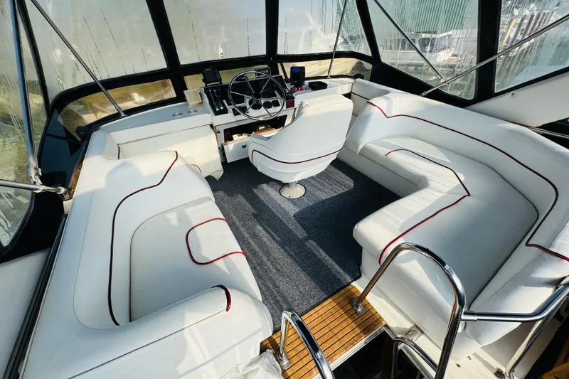 Slide: The Image of 1990 Bayliner 3888 Motoryacht interior with white seating and helm station. - 13