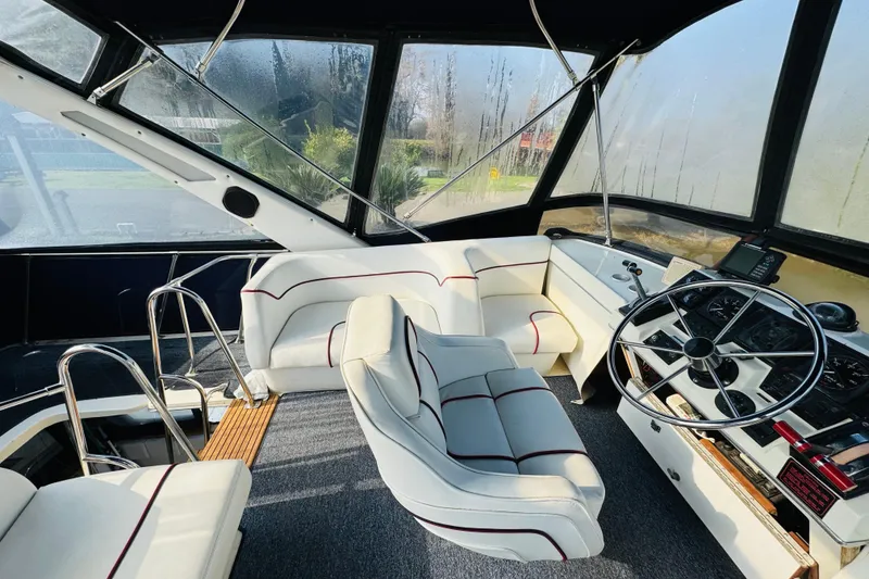 Slide: The Image of 1990 Bayliner 3888 Motoryacht helm with white seating and steering wheel, enclosed cockpit. - 16
