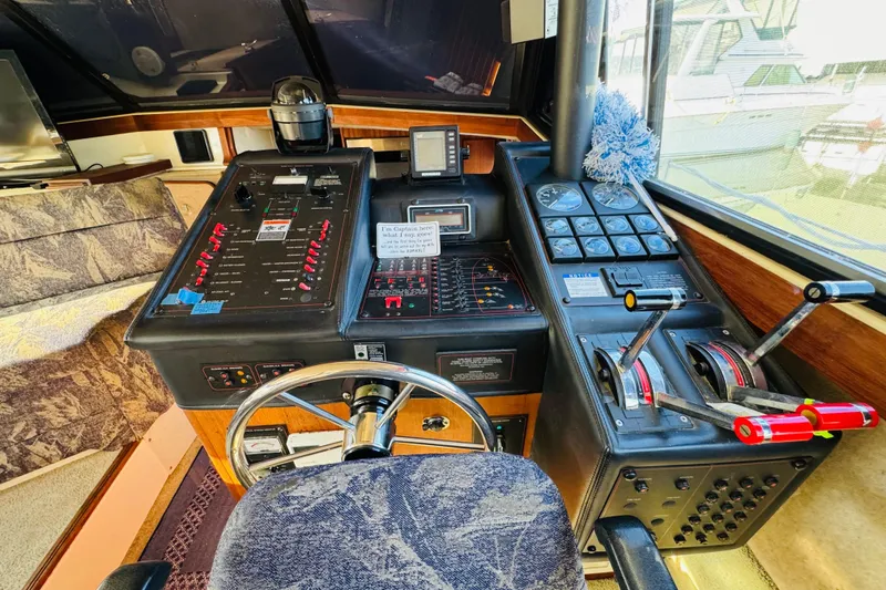 Slide: The Image of 1990 Bayliner 3888 Motoryacht helm with steering wheel, control panels, and navigation instruments. - 25