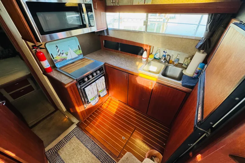 Slide: The Image of 1990 Bayliner 3888 Motoryacht kitchen with wooden cabinetry, stove, and sink. - 27