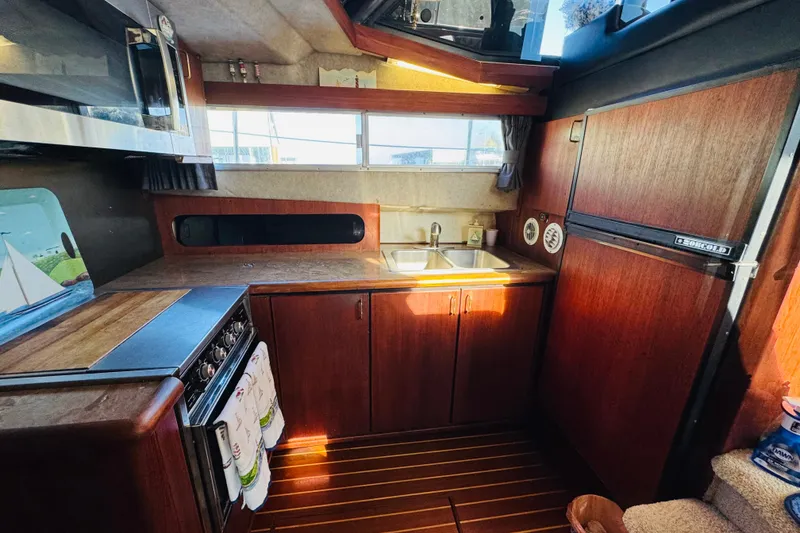 Slide: The Image of 1990 Bayliner 3888 Motoryacht kitchen with wood cabinetry, dual sink, and appliances. - 28